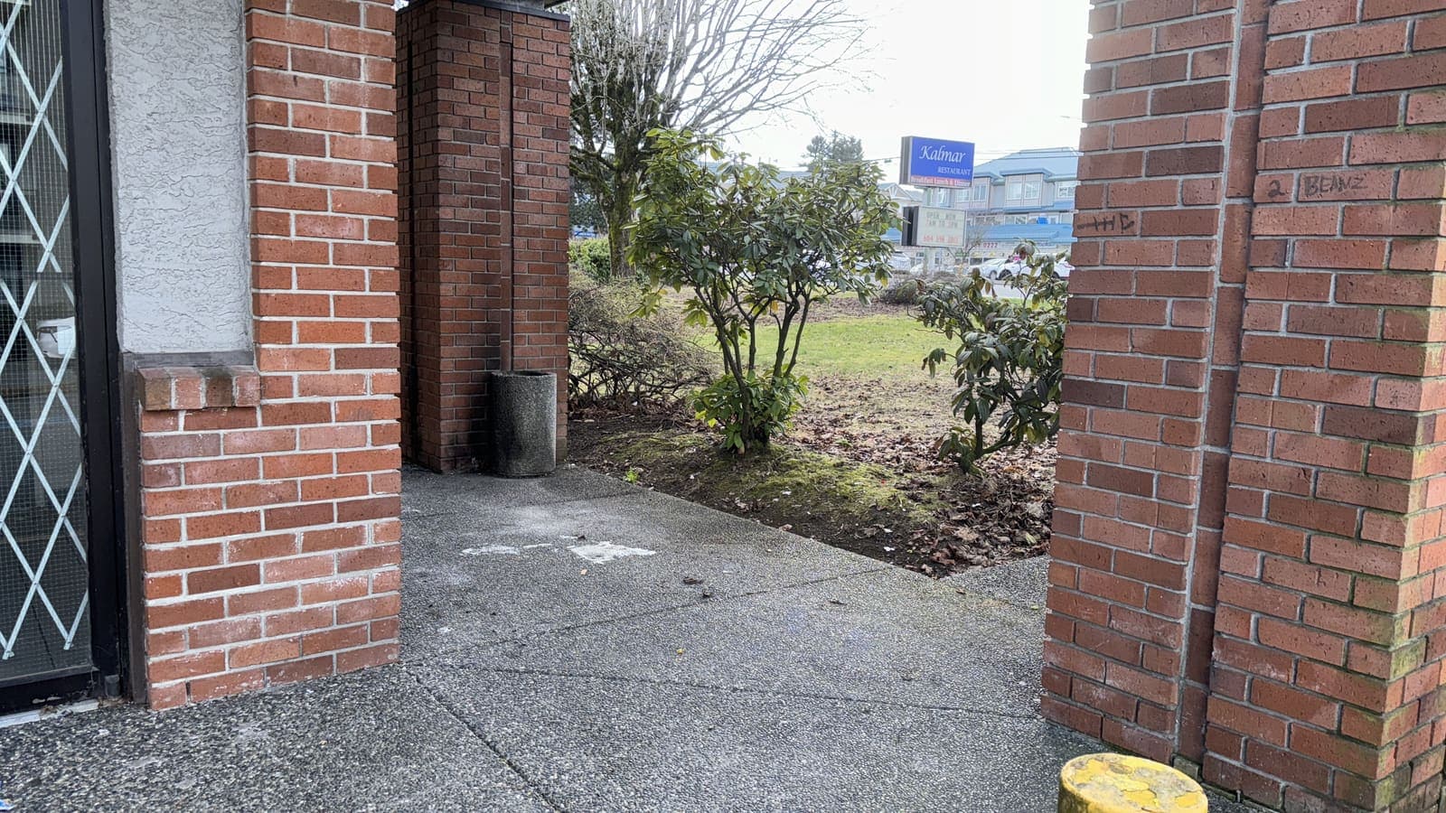 Moss and dirt at a brick commercial building corner before cleaning