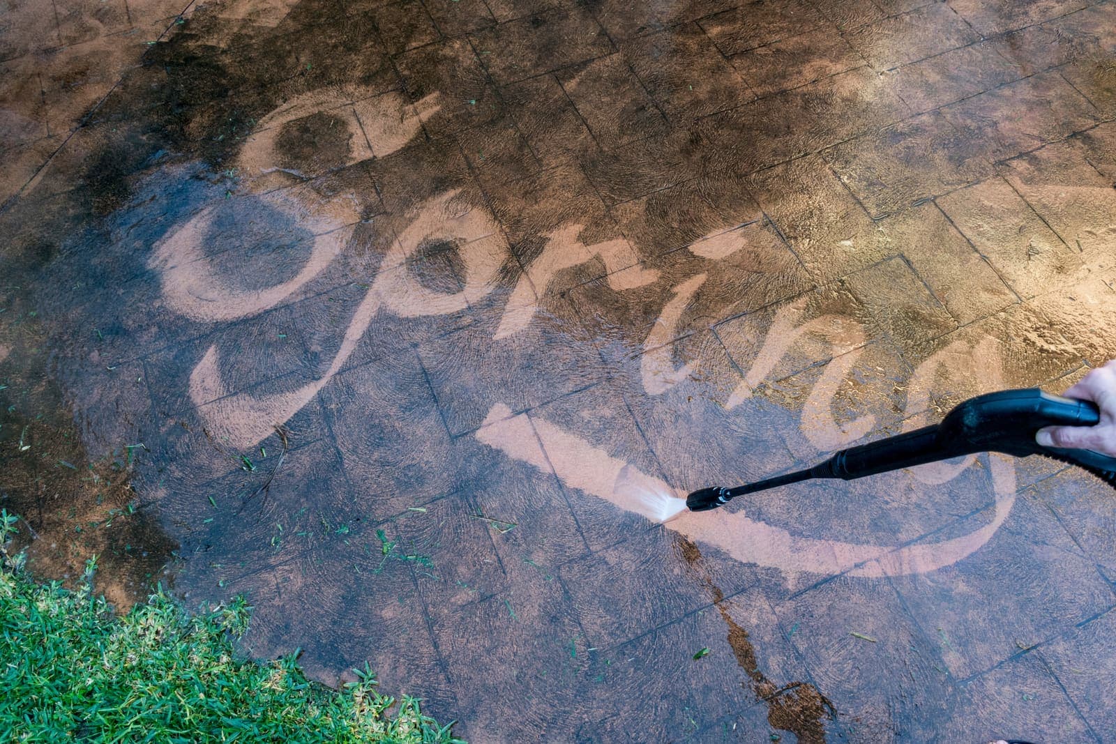 Surface cleaner cutting clean lettering into a mossy concrete slab
