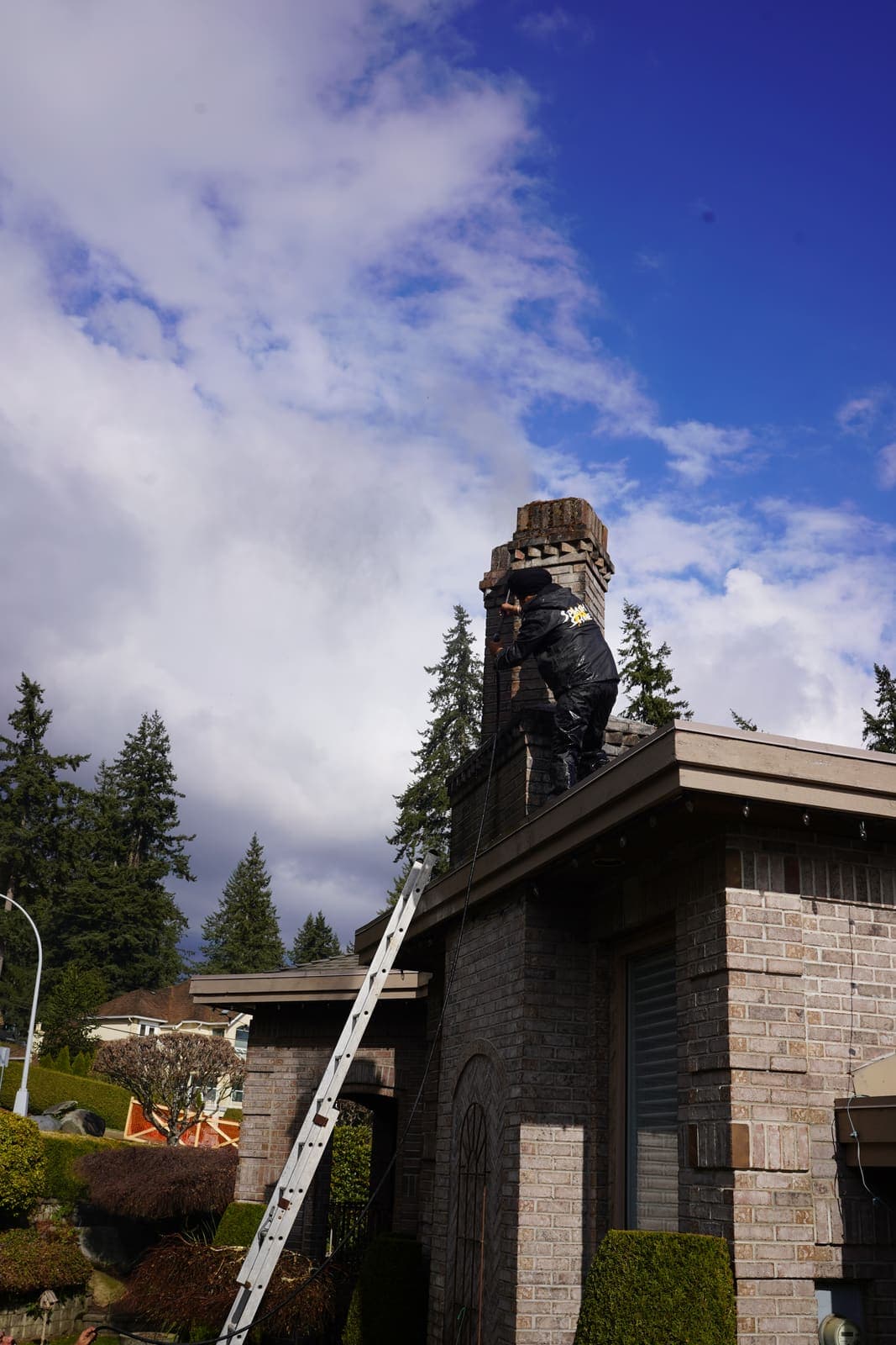 Technician working on the roof of a stone house near the chimney