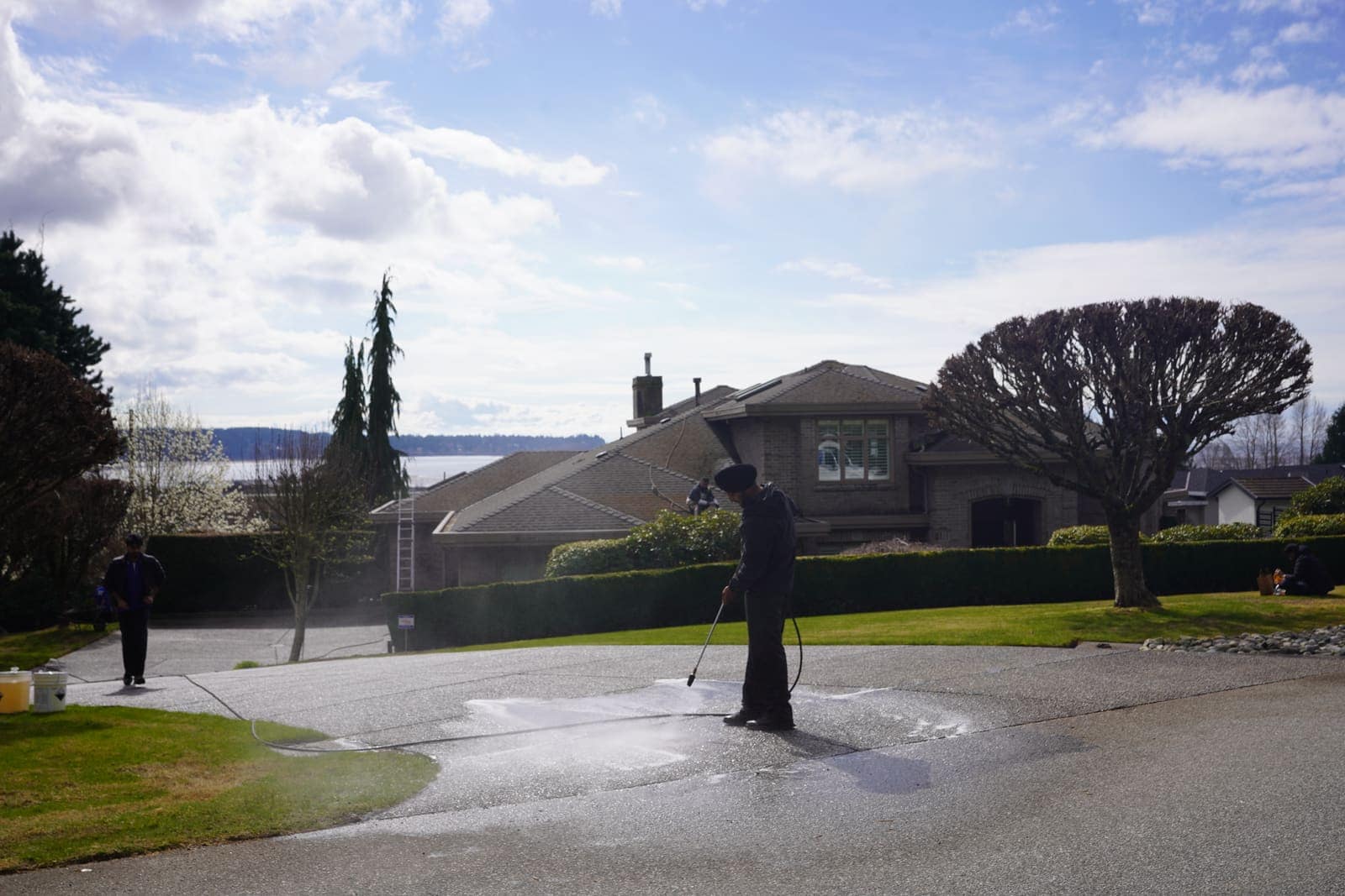 Technician pressure washing the driveway of an ocean-view home