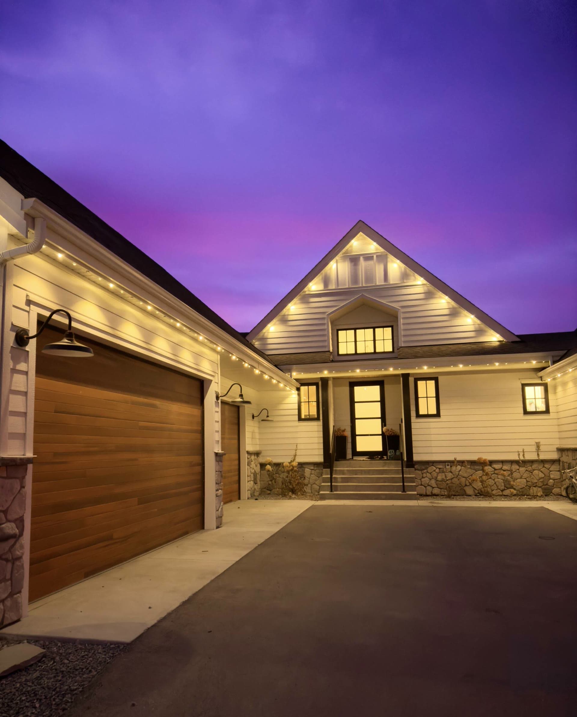 Modern home with clean white permanent lights tracing the rooflines at night
