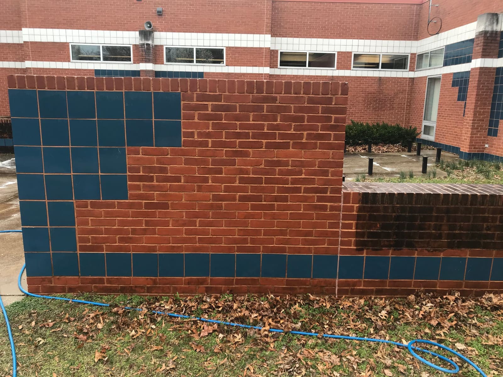 Commercial brick and tile wall being cleaned, half the graffiti of grime already removed