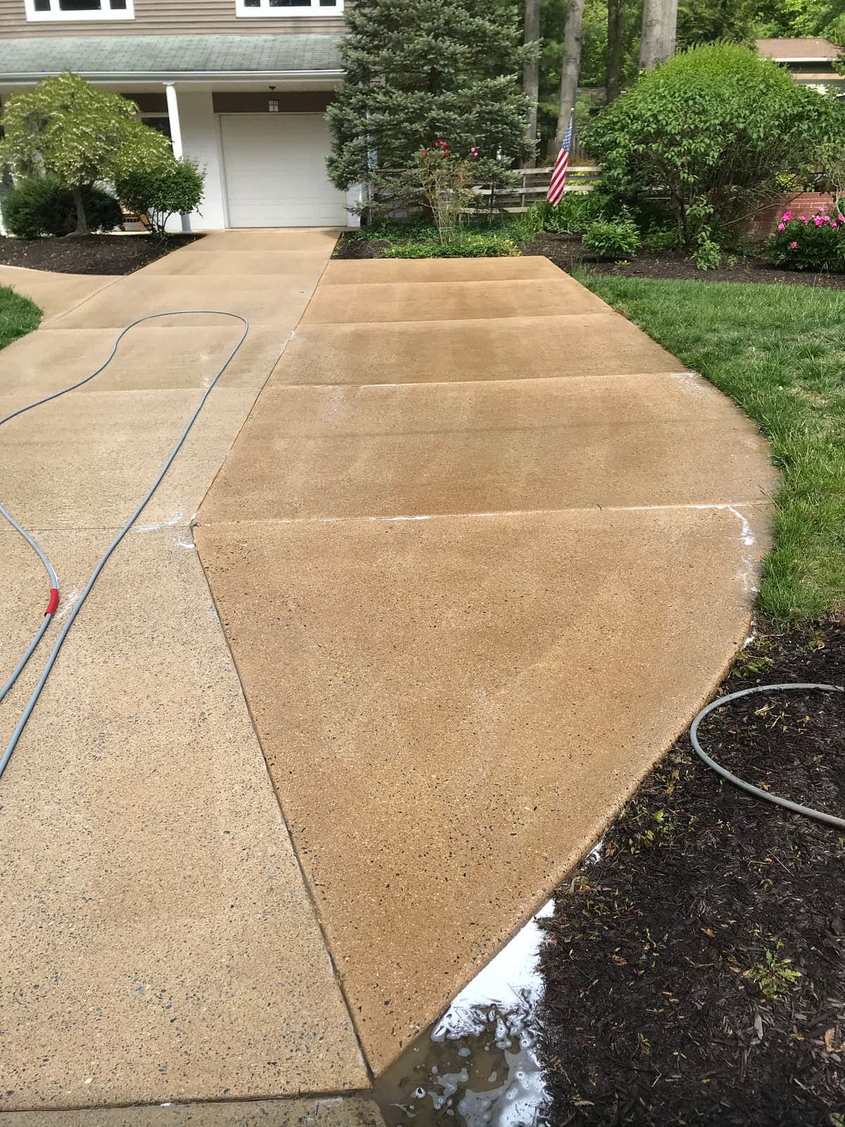 Exposed aggregate driveway half cleaned, showing the sharp line between washed and dirty concrete