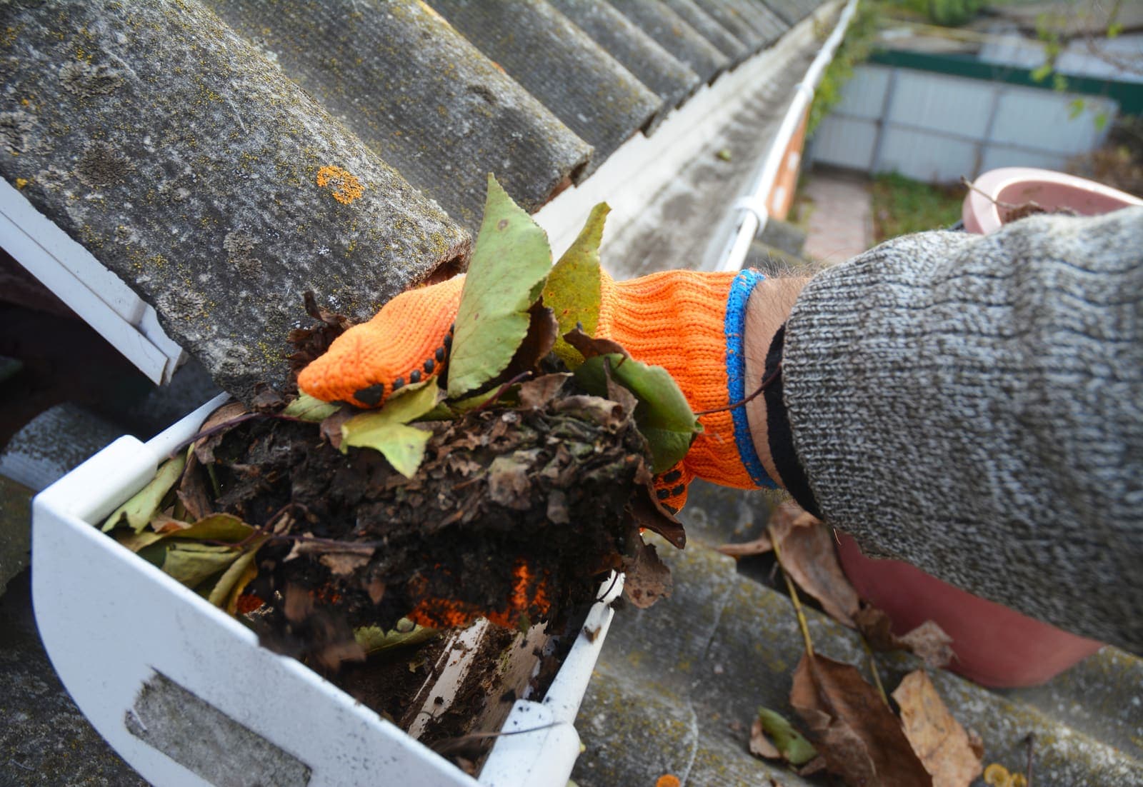 Technician hand-removing wet leaves and debris from a clogged gutter during a professional gutter cleaning — Gutter Cleaning in Coquitlam, BC