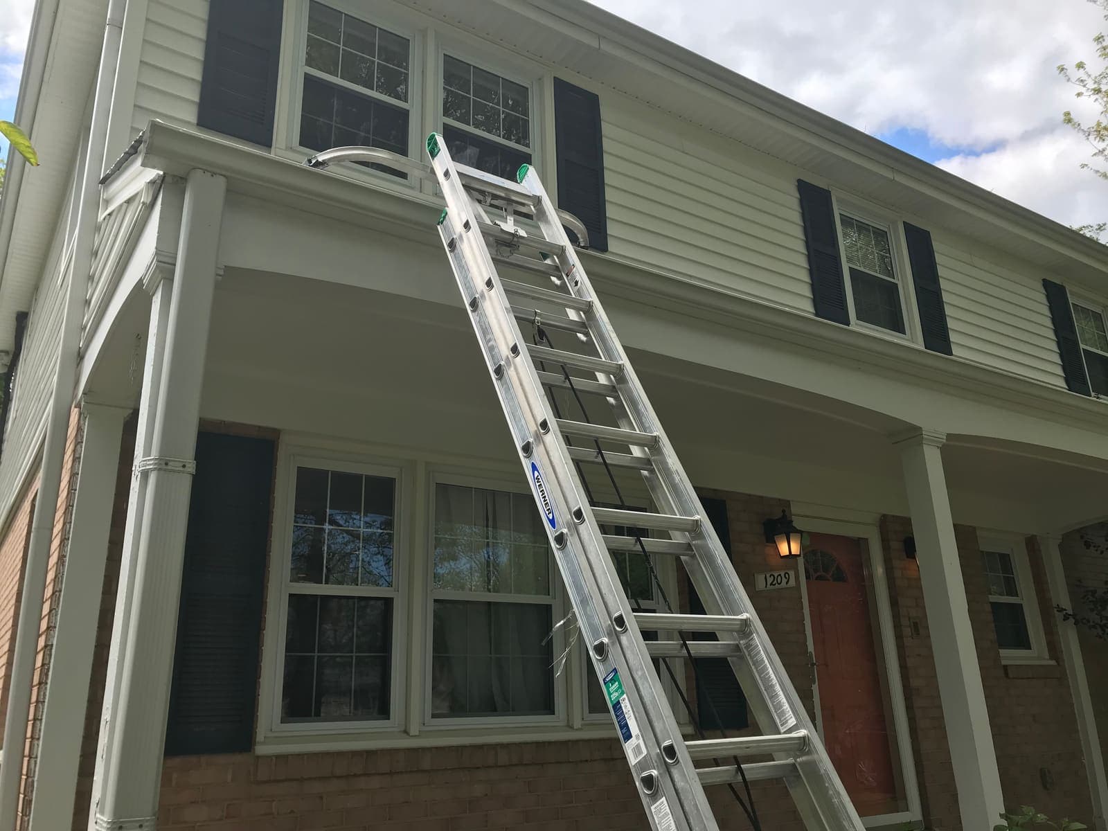 Technician on a ladder clearing a gutter run to protect the fascia below