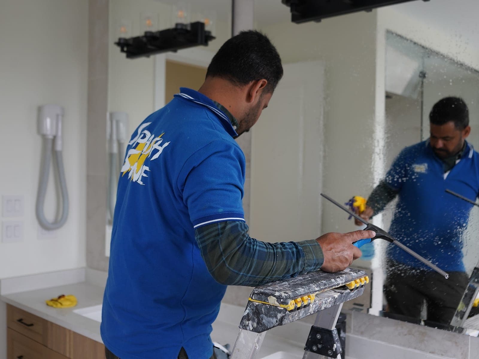 Splash N Shine technician drawing a professional squeegee across a pane of glass, leaving a clean streak-free edge