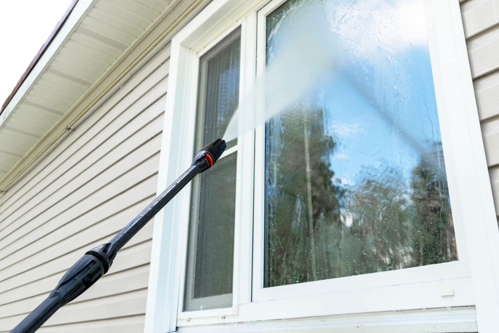 Exterior window being rinsed clear of pollen film with a water-fed cleaning wand
