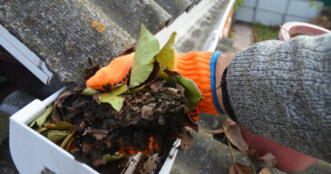 A,Man,Is,Cleaning,A,Clogged,Roof,Gutter,From,Dirt,